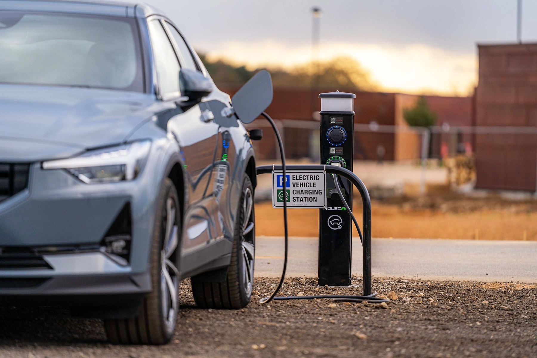 A car charging at dusk outside a commercial building